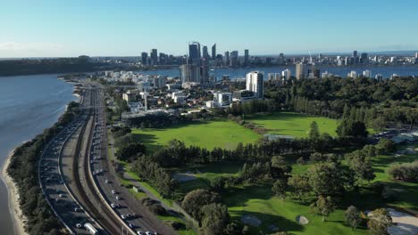 Beautiful-skyline-of-Perth-Downtown-with-traffic-on-highway-beside-golf-club-and-South-Perth-City-District---Aerial-view