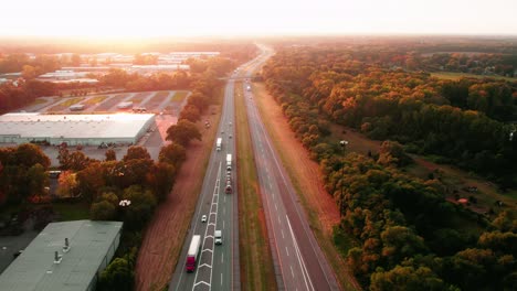 Zauberhafte-Luftaufnahmen-Bei-Sonnenuntergang-Von-LKW-Fracht,-Die-Mit-Sattelschleppern-Und-Anhängern-Auf-Der-Interstate-I-80-In-Elkhart,-Indiana,-Transportiert-Wird