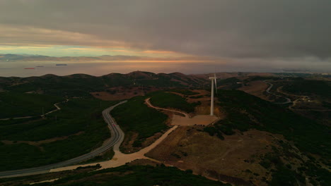 Aerial-dolly-to-wind-turbine-overlook-strait-of-Gibraltor,-storm-rolls-in-over-ocean