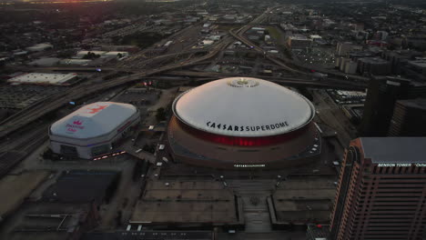 Aerial-view-tilting-away-from-the-Caesars-Superdome,-sunset-in-New-Orleans,-USA