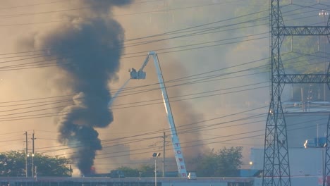 Operation-of-firefighter-on-crane-against-massive-fire-and-billowing-smoke