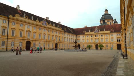 Yellow-Façade-of-Melk-Abbey-with-Tourists-Walking-Around