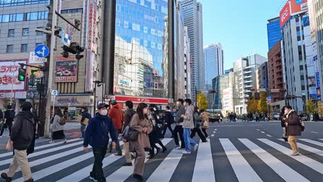 Crowd-of-people-crossing-a-busy-road-crossing-in-Shinjuku-Toyko,-Japan