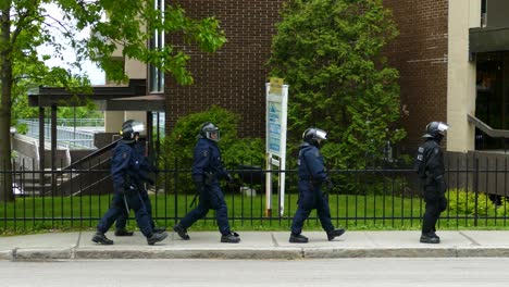 Group-Of-Riot-Police-Walking-In-The-Sidewalk-During-The-G7-Summit-In-Quebec-City,-Canada