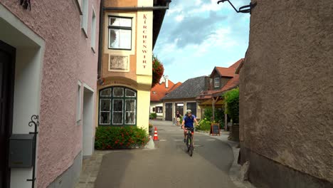 Cyclist-Passes-By-in-old-town-of-Weisskirchen,-in-the-Wachau-region-of-Austria
