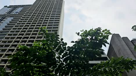 Trucking-shot-of-tall,-commercial-buildings-and-trees,-Manila-Philippines