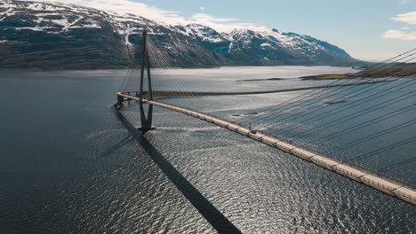 4K-drone-wide-shot-with-parallax-motion-of-calm-fjord-and-the-majestic-bridge-in-Helgeland,-a-famous-tourist-attraction-on-the-Norwegian-scenic-tourist-route-Helgelandskysten,-Helgelandsbrua,-Norway