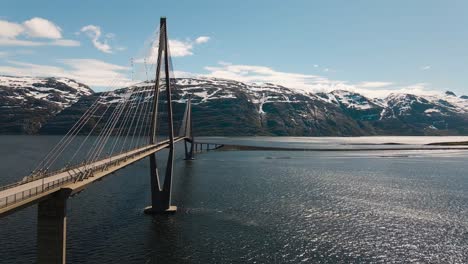 4K-drone-wide-shot-with-parallax-motion-of-calm-fjord-and-the-majestic-bridge-in-Helgeland,-a-famous-tourist-attraction-on-the-Norwegian-scenic-tourist-route-Helgelandskysten,-Helgelandsbrua,-Norway