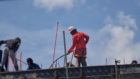 Several-construction-workers-doing-concrete-pouring-at-the-rooftop-of-a-construction-building