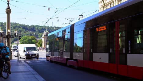 Modern-design-red-streetcar-with-marked-routes-on-the-paved-streets-of-Prague,-Czech-Republic-with-cars-on-the-track