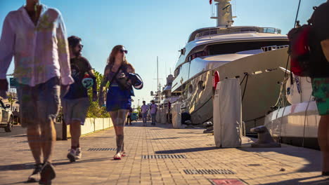 Yacht-Vor-Anker-Im-Hafen-Von-Malaga-In-Spanien-Mit-Menschen,-Die-Im-Sommer-Auf-Der-Promenade-Spazieren-Gehen