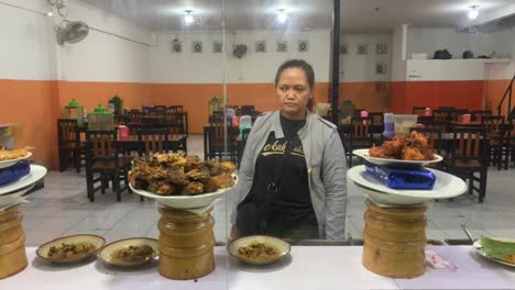 Asian-woman-in-"Berkah-Dalem"-or-God-Bless-t-shirt-is-choosing-a-food-in-Padang-stall
