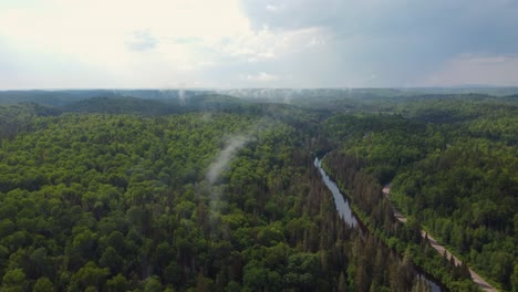 Dünne-Neblige-Wolken-über-Dichtem-Wald-Mit-Flusslauf-In-Der-Nähe-Von-Muskoka-In-Ontario,-Kanada
