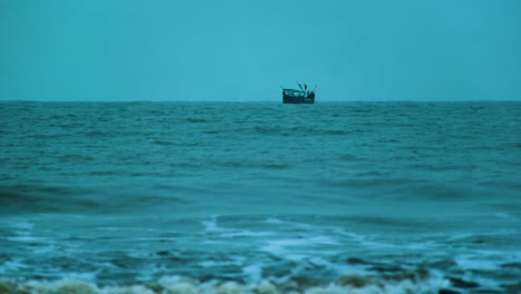 Fishing-Trawler-Boat-out-to-Sea,-with-Waves-Crashing-in-the-Foreground-and-the-Wind-Picking-Up,-Bangladesh