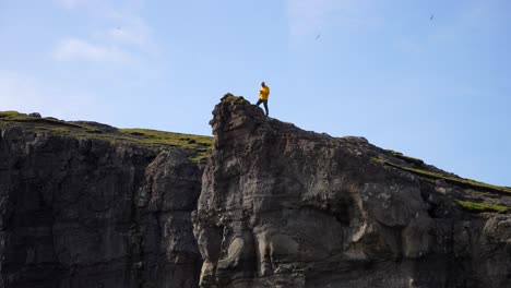 Man-taking-photo-of-Faroese-landscape-from-Traelanipa-cliff-edge-in-Faroe-Islands