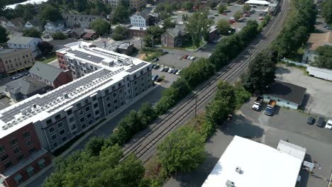 Aerial-dolly-tilt-up-above-train-tracks-and-apartment-building-with-solar-panels,-Northampton-Massachusetts