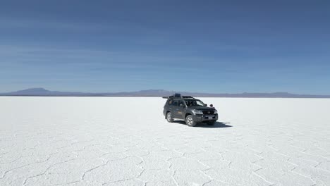 Aerial-orbiting-around-travelers-camping-in-the-Salar-Salt-Flats-in-Uyuni,-Bolivia
