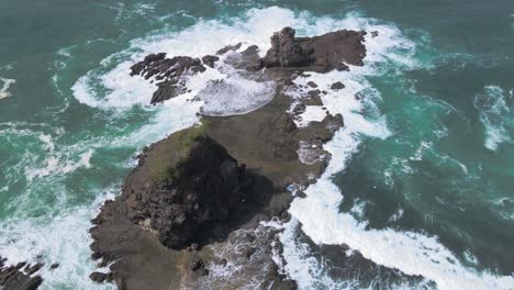 Aerial-forward-drone's-view-of-a-rock-hit-by-waves