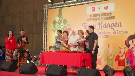 Group-of-people-participating-in-cutting-tumpeng-ceremony-on-stage