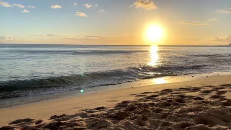 Die-Strahlend-Goldene-Sonne-Wirft-Einen-Lichtstrahl-über-Das-Offene-Meer,-Während-Sanfte-Wellen-An-Den-Sandstränden-Von-Hawaii-Brechen