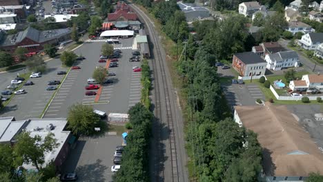 Drone-flies-along-train-tracks-approaching-Northampton-Massachusetts-station-parking-lot