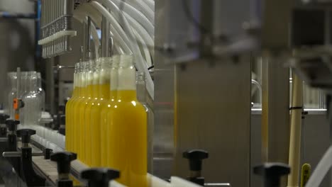 Witness-the-rhythmic-dance-of-bottles-filled-with-vibrant-citrus-juice-gliding-along-a-conveyor-line,-a-symphony-of-freshness-and-efficiency-in-this-captivating-production-scene