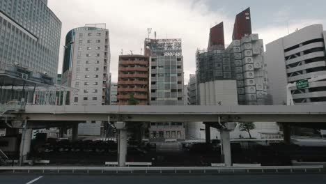 The-Nakagin-Capsule-Tower-Building-being-demolished-with-a-raised-highway-in-the-foreground-with-traffic-passing-by