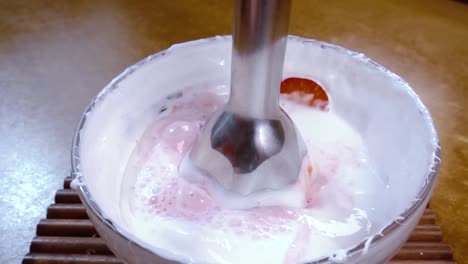 Beaten-eggs-with-sugar-and-strawberries-using-a-mixer.Slow-motion-with-rotation-tracking-shot.