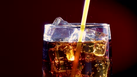 Cola-and-drink-tube-with-Ice-and-bubbles-in-glass.