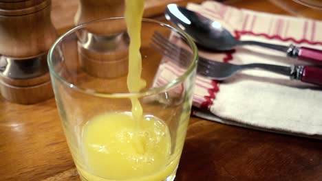 Orange-juice-pouring-into-a-glass,-the-morning-Breakfast.-Slow-motion-with-rotation-tracking-shot.