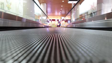 Moving-walkway-at-the-airport,-also-known-as-an-autowalk,-moving-sidewalk,-moving-pavement,-people-mover,-travolator,-or-travelator,-is-a-slow-moving-conveyor-mechanism-that-transports-people.