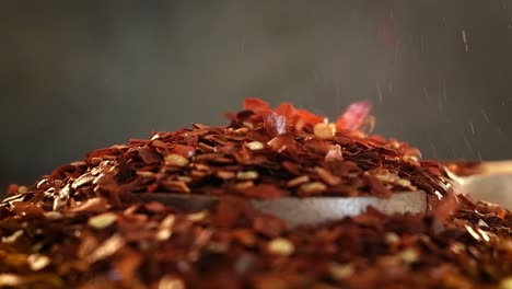 Flakes-of-red-hot-chili-pepper-in-wooden-spoon-closeup-on-a-kitchen-table.