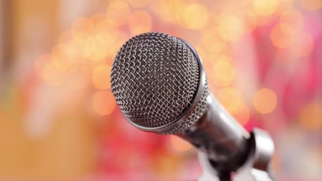 Microphone-on-stage-against-a-blurry-light-,blurry-background.