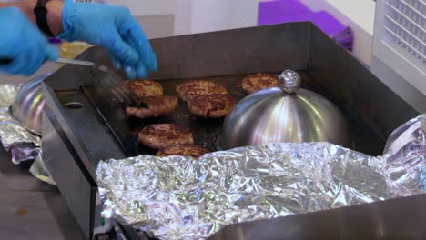 Meat-beef-patty-is-cooked-in-a-hot-frying-pan.-Street-food,-chef-flips-burgers-with-a-spatula.