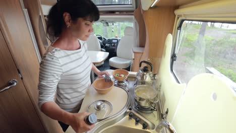 Woman-cooking-in-camper,-motorhome-interior