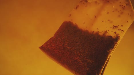 Close-up-of-tea-bag-diffusing-in-a-clear-glass.-Macro-slow-motion-shot-of-the-process-of-brewing-herbal.