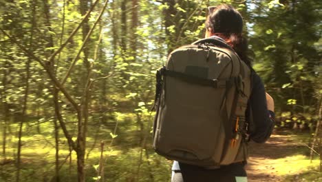 Hiking-woman-walk-with-a-hiking-backpack-in-spring-green-forest