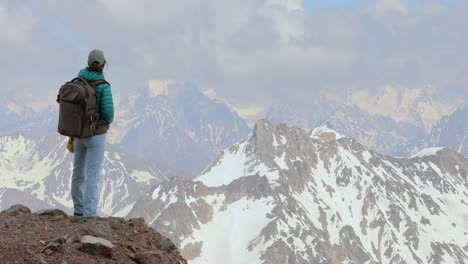 Hiker-woman-standing-up-achieving-the-top.-View-at-the-snowy-mountains.