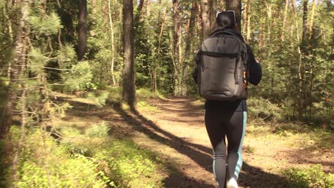 Hiking-woman-walk-with-a-hiking-backpack-in-spring-green-forest