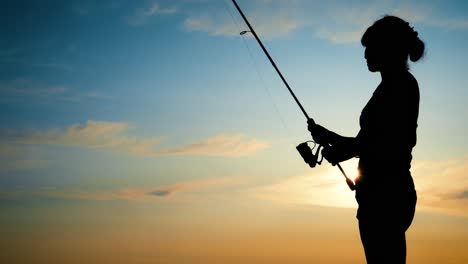 Woman-fishing-on-Fishing-rod-spinning-at-sunset