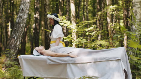 Therapist-female-doctor-making-woman-relaxing-spa-face-massage-with-hands-outdoors-in-the-forest