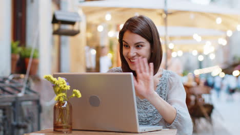 Woman-using-laptop-having-video-call-chat-conversation-for-online-meeting-in-urban-city-cafe-terrace