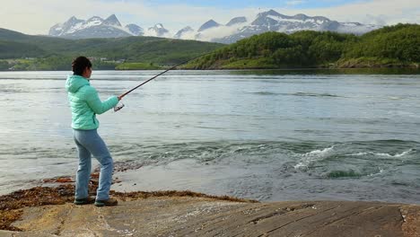 Una-Mujer-Atrapó-Un-Pez-Grande-Con-Una-Caña-De-Pescar-Y-No-Puede-Sacarlo-Del-Agua.-Pescando-Con-Caña-De-Pescar-Girando-En-Noruega.-Pescar-En-Noruega-Es-Una-Forma-De-Adoptar-El-Estilo-De-Vida-Local.