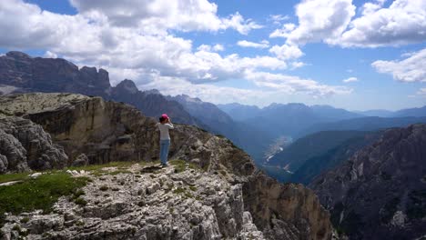 Hiker-woman-standing-up-achieving-the-top-Dolomites-Alps.