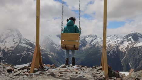 Woman-goes-for-a-drive-on-a-swing-against-a-background-of-mountains.-Slow-motion-video.