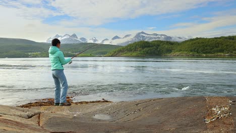 Woman-caught-a-big-fish-on-a-fishing-rod-and-can-not-pull-it-out-of-the-water.-Fishing-on-Fishing-rod-spinning-in-Norway.-Fishing-in-Norway-is-a-way-to-embrace-the-local-lifestyle.