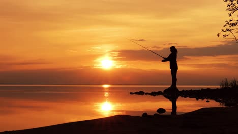 Woman-fishing-on-Fishing-rod-spinning-at-sunset-background.