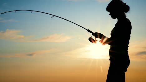 Woman-fishing-on-Fishing-rod-spinning-at-sunset.-A-woman-caught-a-fish,-but-she-fell-off-the-hook.