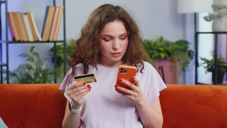 Young-woman-using-credit-bank-card-and-smartphone,-transferring-money-purchases-online-shopping