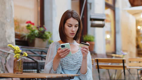 Junge-Frau-Benutzt-Smartphone-Mit-Kreditkarte,-Während-Sie-In-Der-Cafeteria-Geldanweisungsessen-überweist